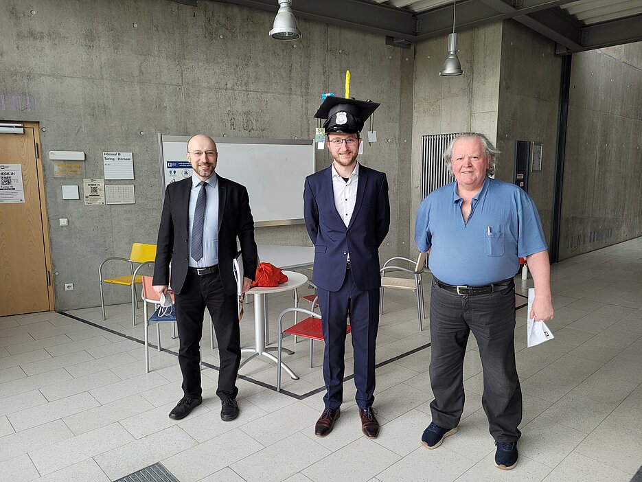 V.l.n.r.:  Prof. Dr.-Ing. Samuel Kounev, Dr. Johannes Grohmann mit Doktorhut, Prof. Dr. Reiner Kolla 